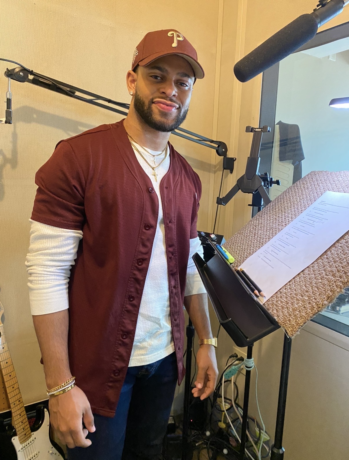Brandon Miles at the microphone in a recording studio, script on the stand beside him