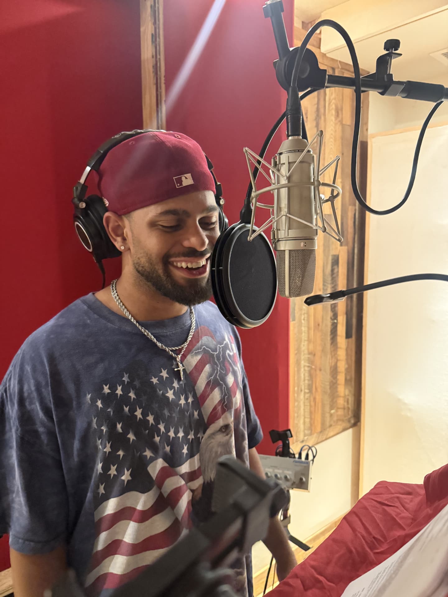 Brandon Miles smiling while recording at a studio microphone